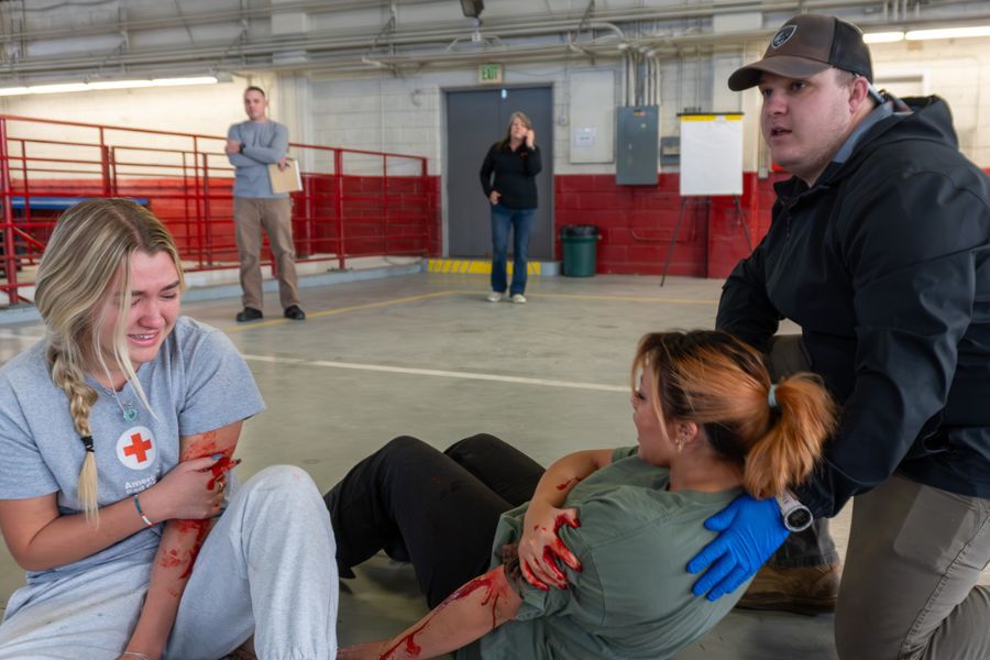Two actors act like they are injured during a simulation training for EMS