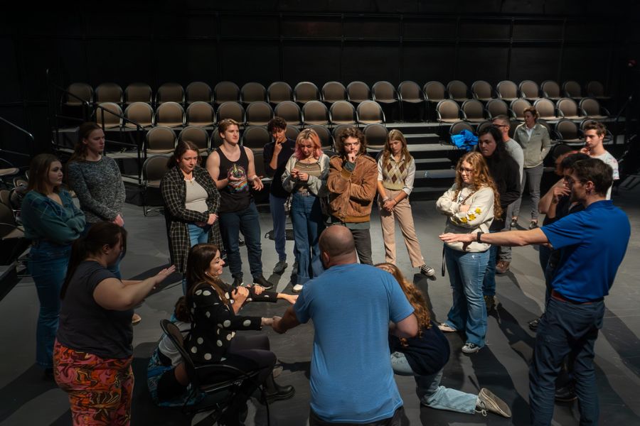 Daniel Haley and a group of students stand in the Black Box Theatre discussing things