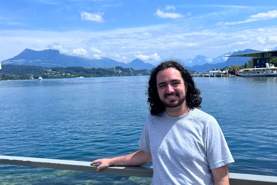 Gabe Lowman stands in front of a body of water in Switzerland
