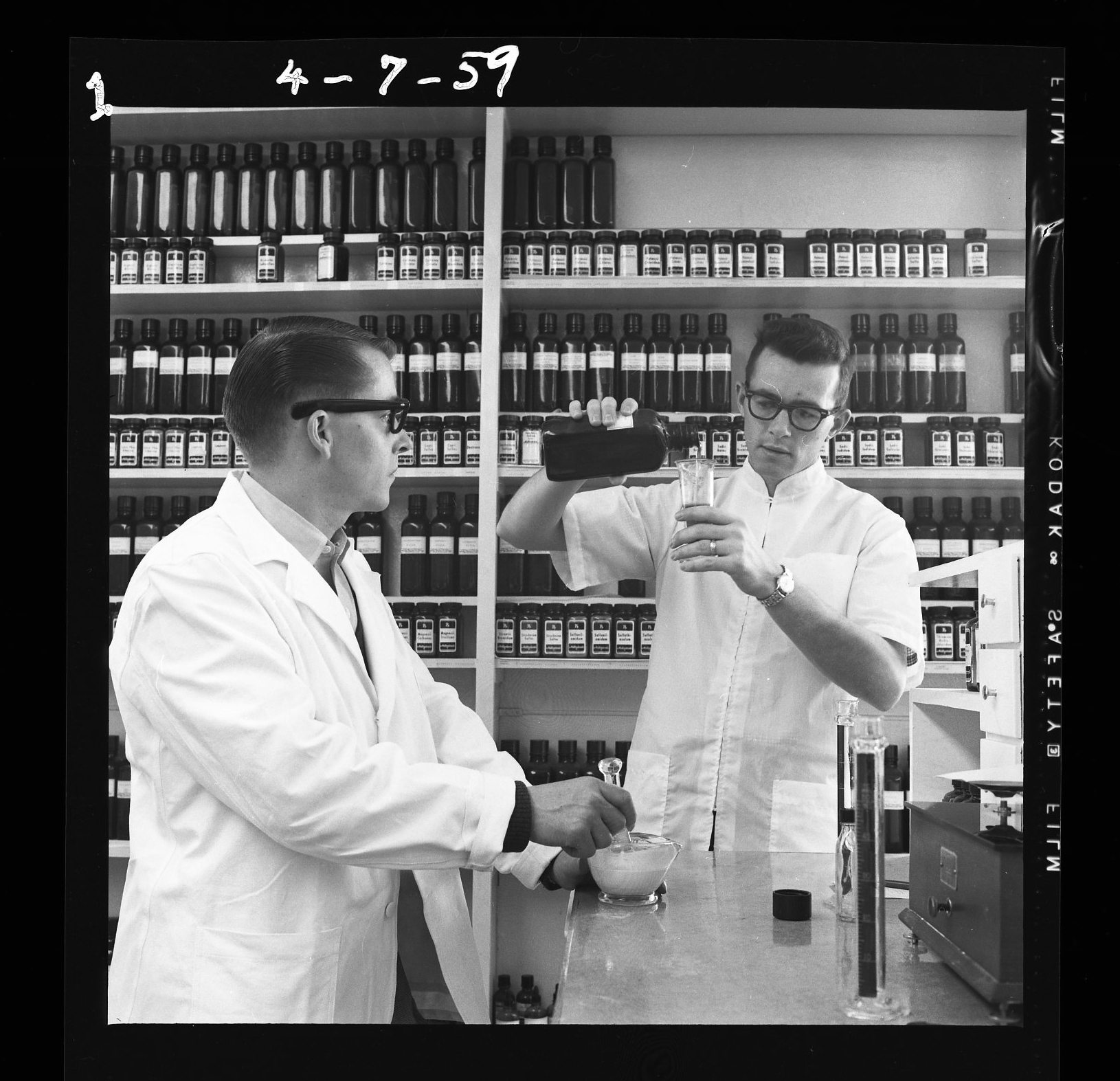 Two male pharmacists prepare a prescription in a historical photo of the College of Pharmacy
