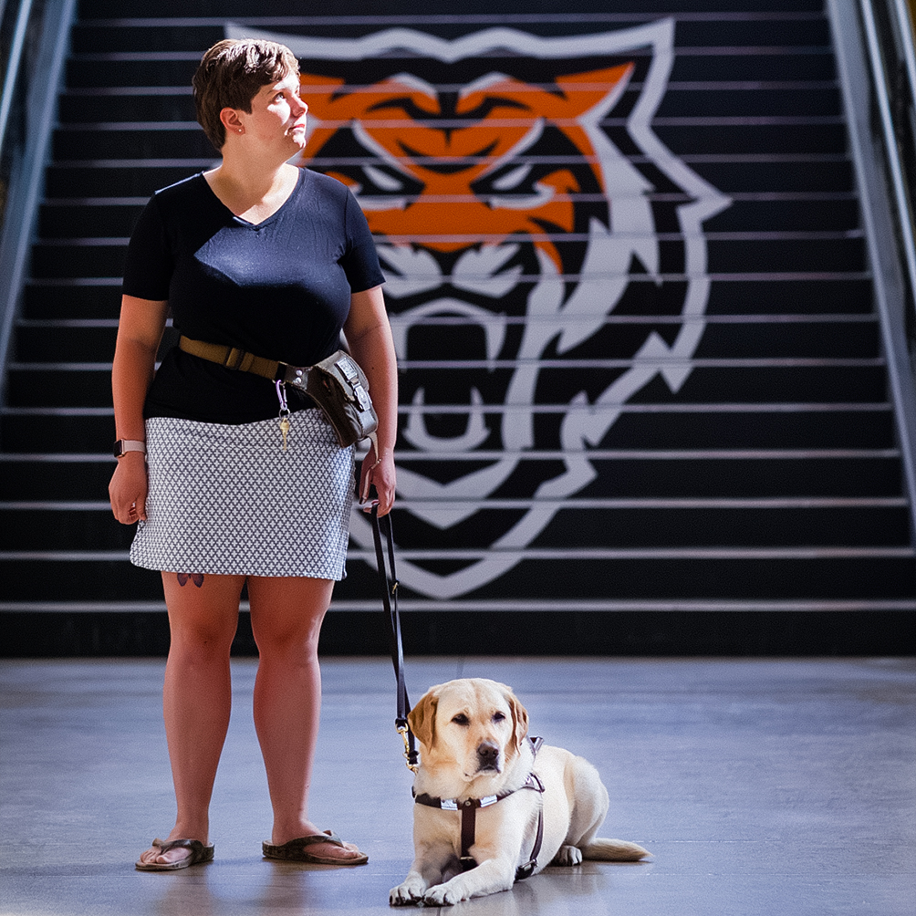 A student standing with a service dog by their side