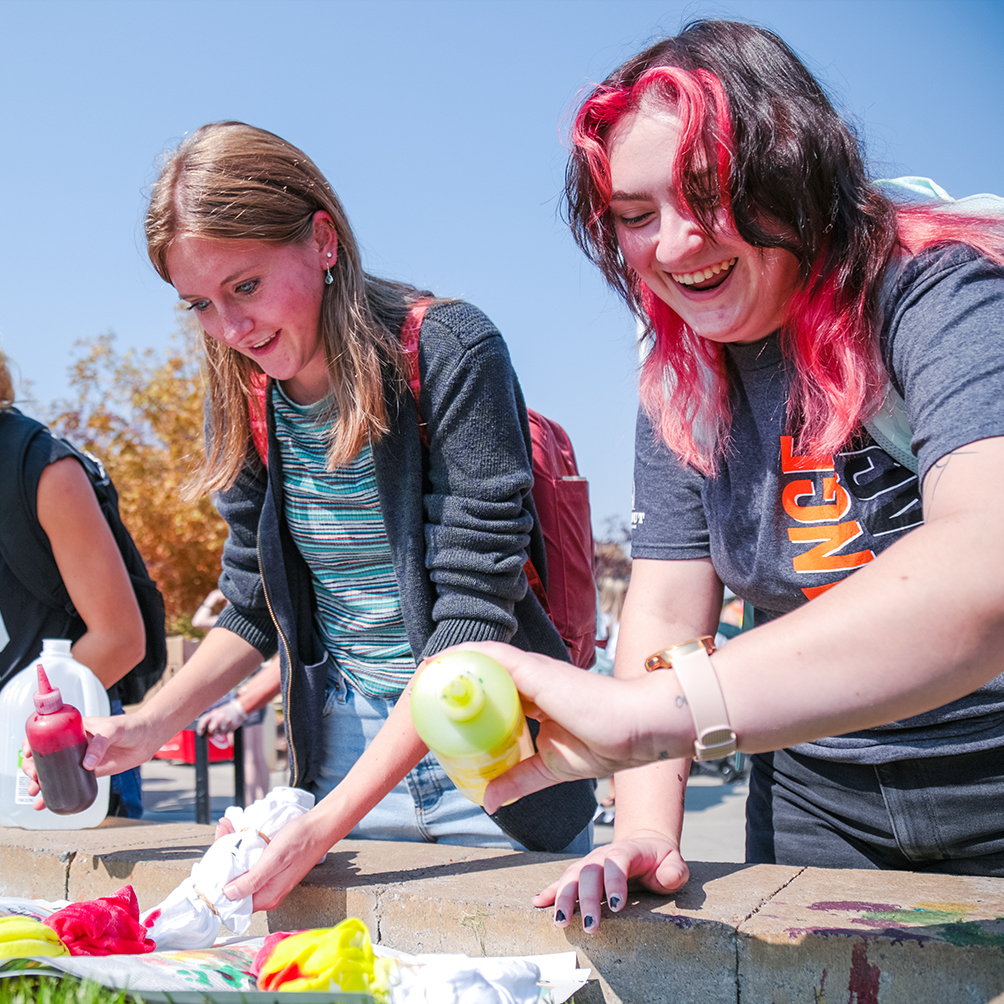 A group of students tye-dyeing shirts.