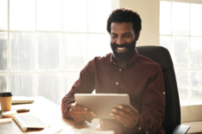 Man smiling while reading tablet