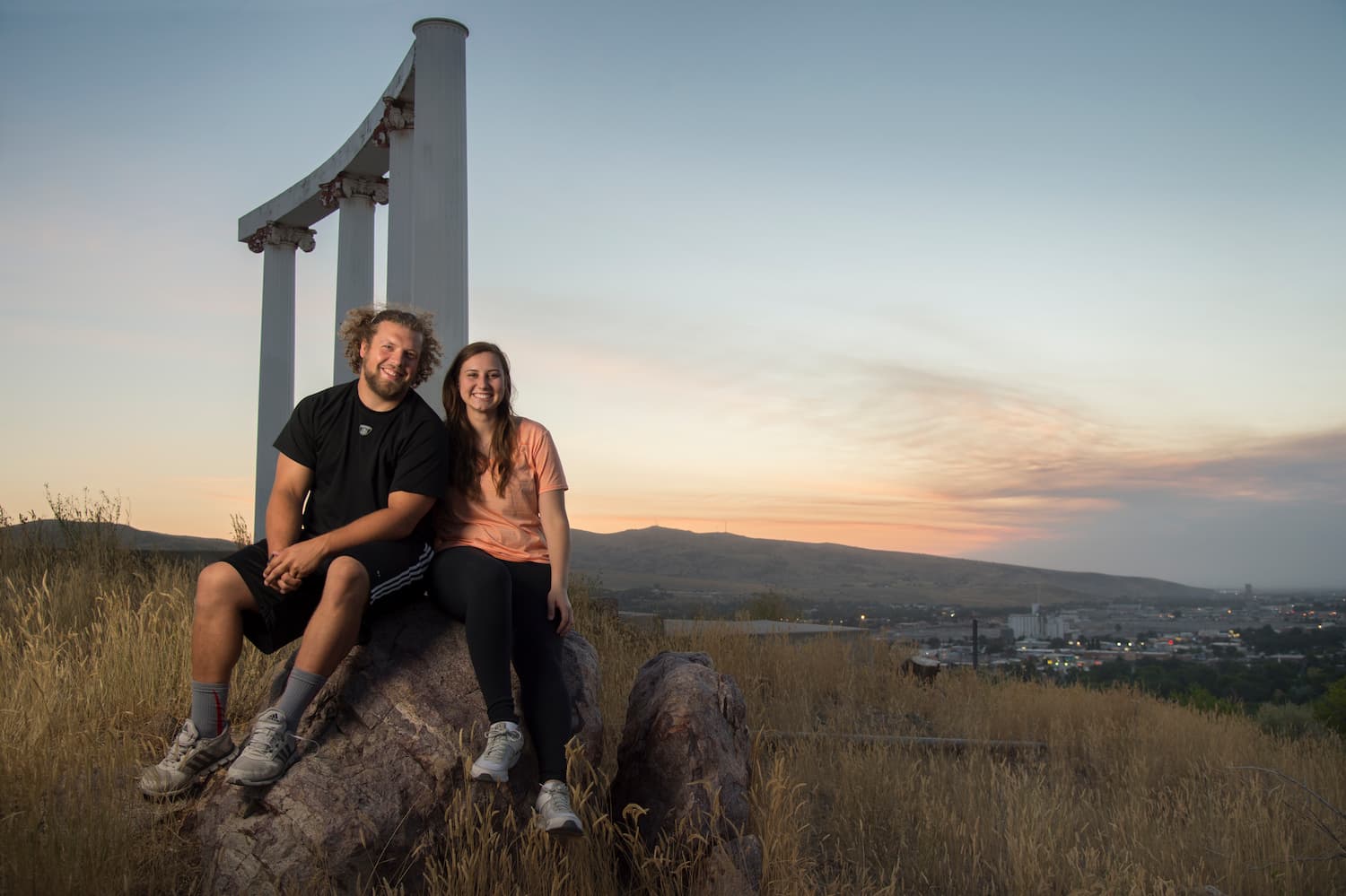 Students sit in front of ISU pillars at dusk