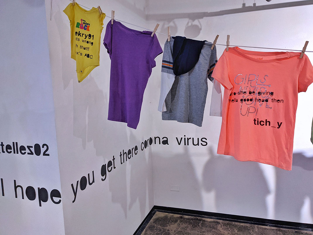In view is a corner of the gallery, across which insulting comments have been printed. A clothesline is partially in view