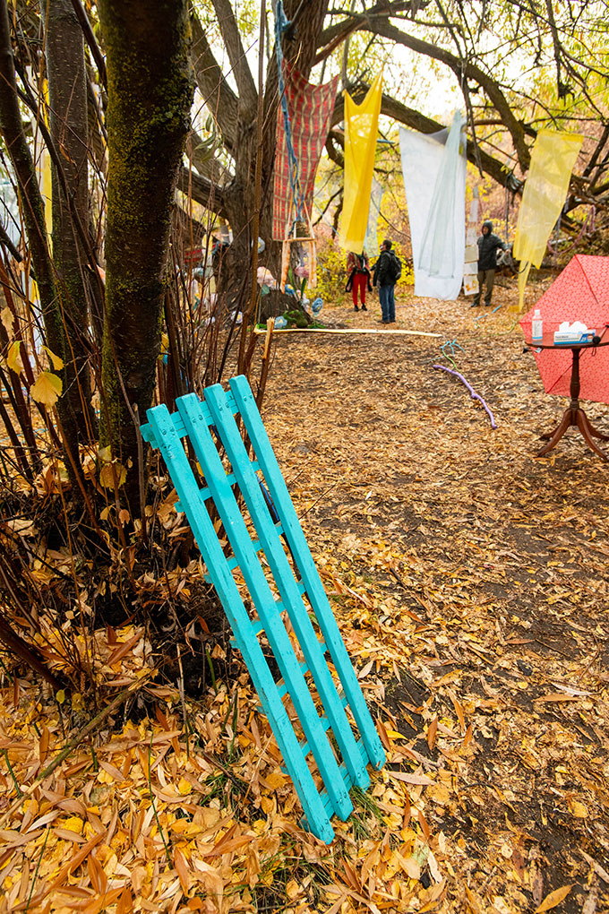 Installation photo - bright cyan wood planks leaning against a tree