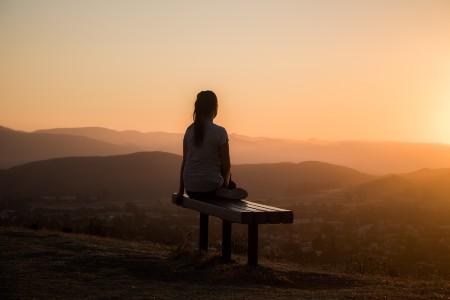 Female sitting on a bench looking over the horizon