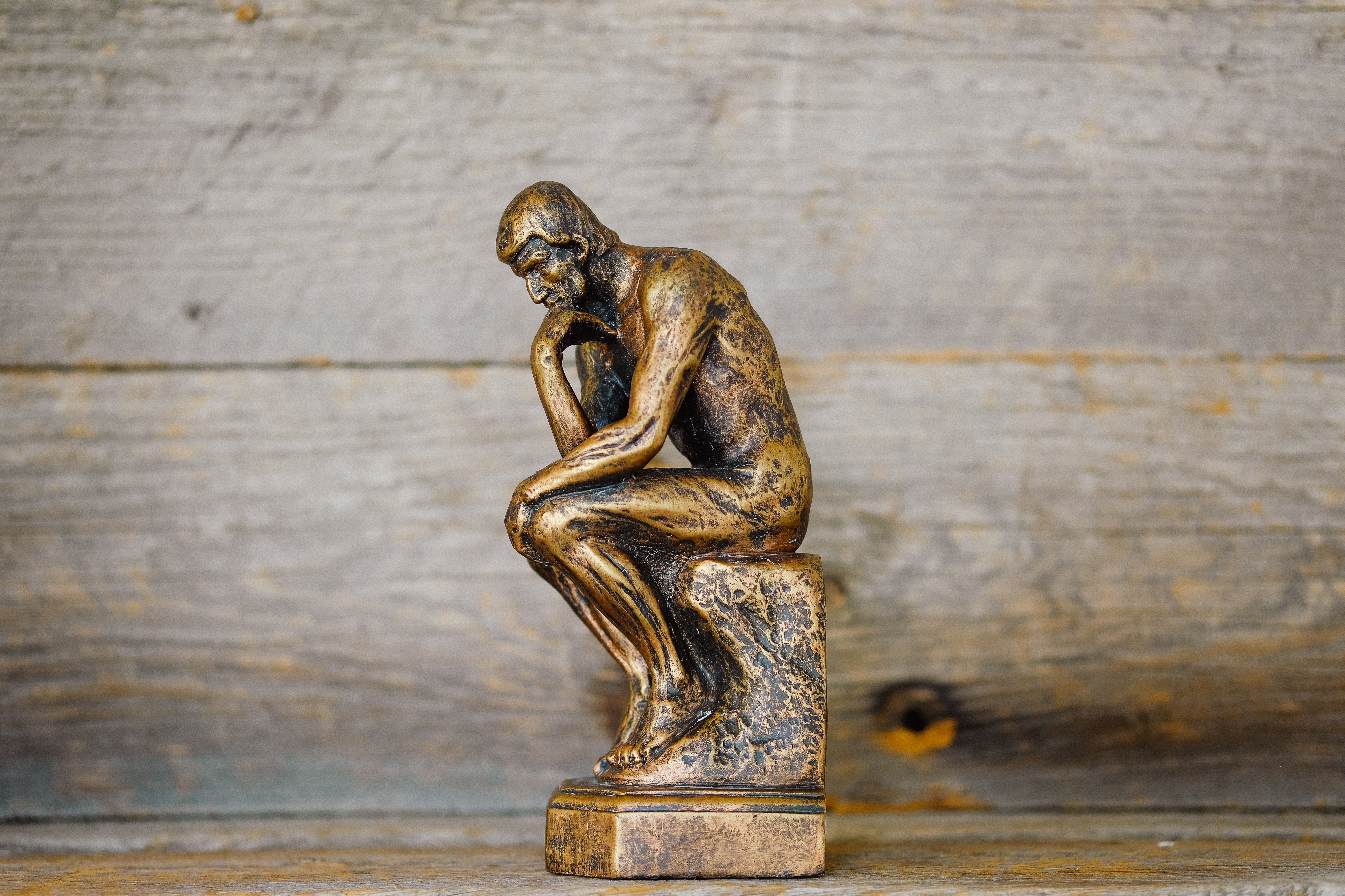 Statue of a man sitting with head in his hand thinking