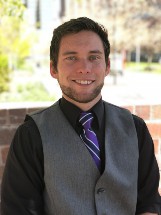 A student in a black shirt and purple tie smiling