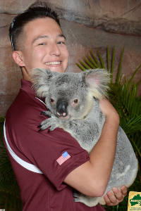 Young man smiles while holding a koala