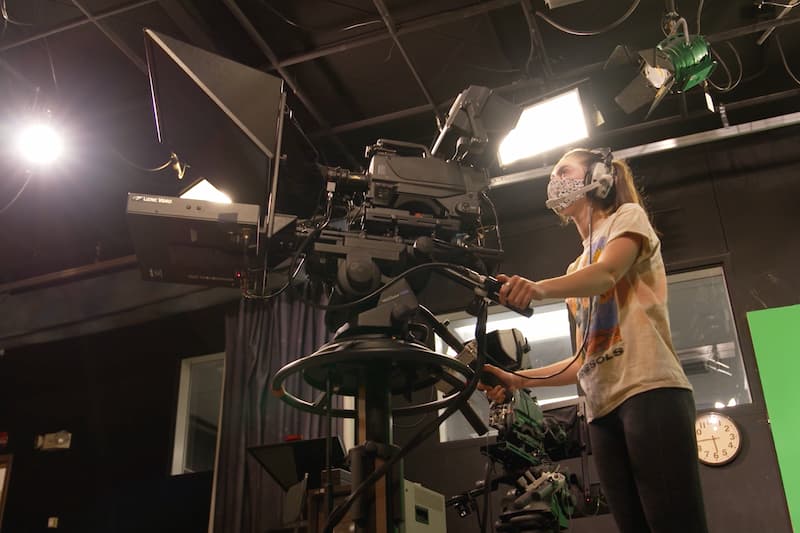A feminine person operating a stage camera