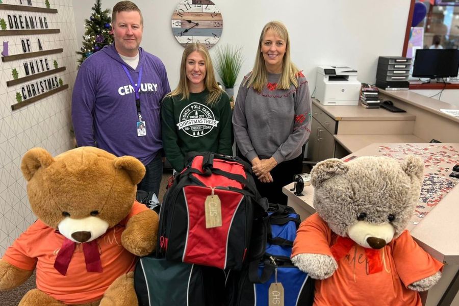 three volunteers stand amidst donations for local high school students