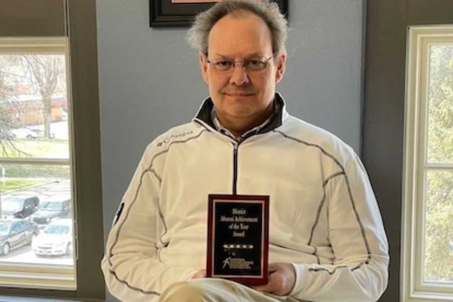 Andy Christensen sits holding his award plaque