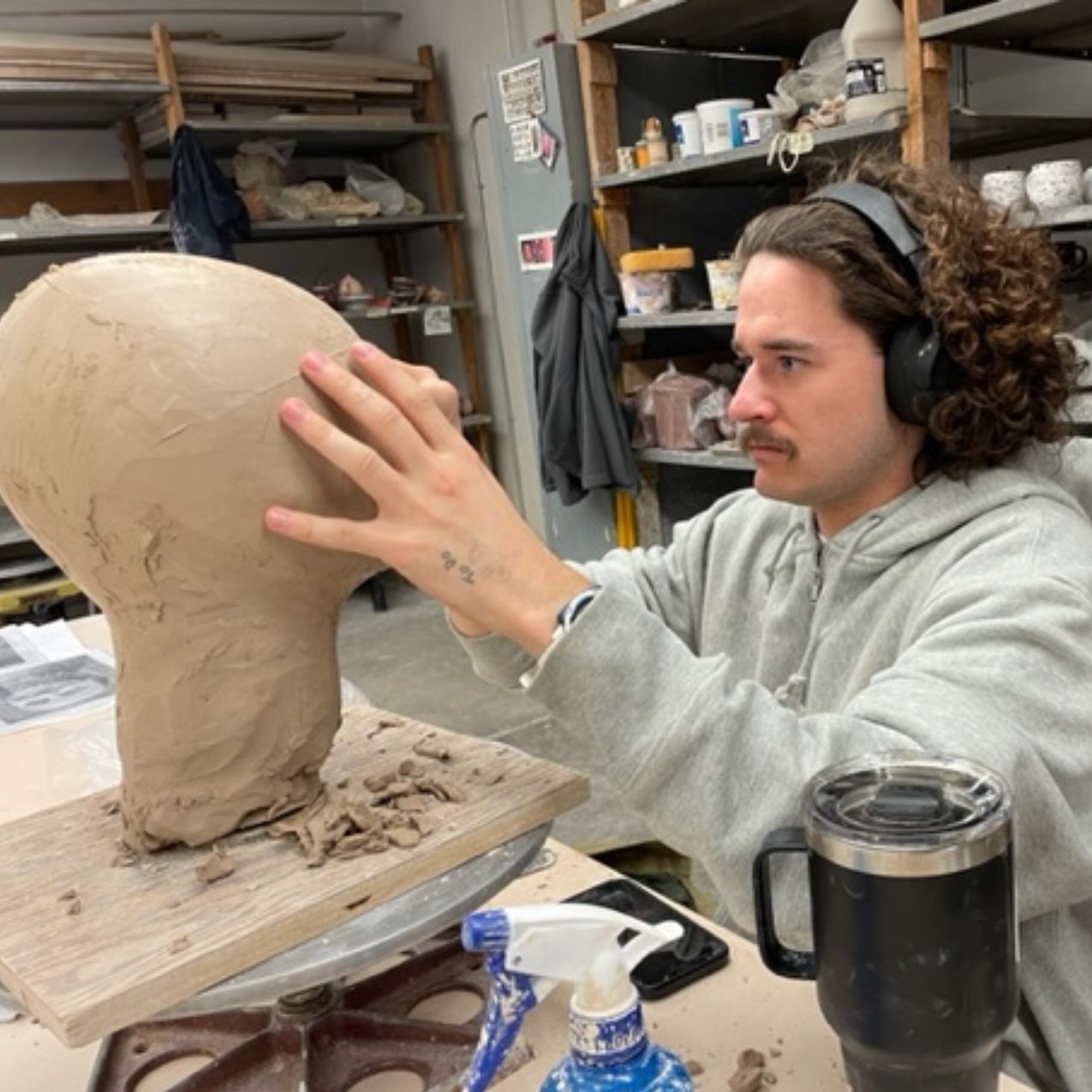 Art student at ISU works on carving a head/face out of clay in the ceramics studio