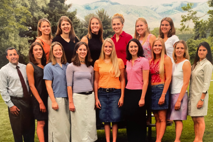 The women's volleyball team of 2017 pose for a portrait. They are standing outside wearing nice clothes and smiling.