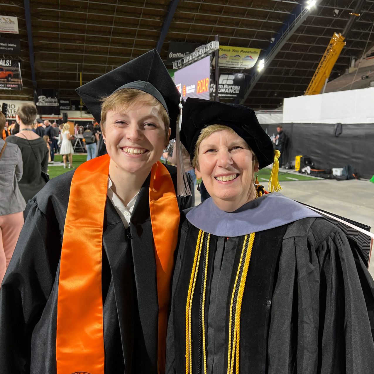 Professor Nancy Legge smiles with a graduate in robes at commencement