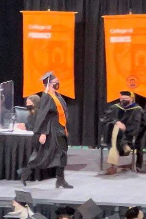Kenzie Michaels walks across the stage at ccommencement in her cap and gown