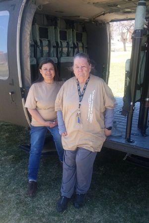 Lillian and Teresa Molina stand in the side door of an army helicopter