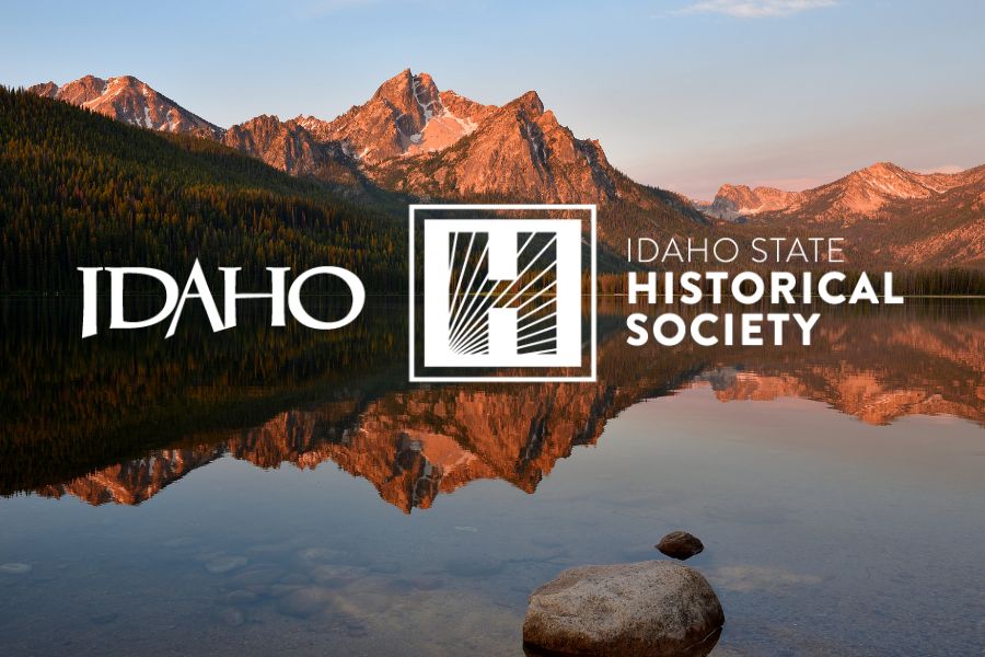 The Idaho Historical Society logo is in front of a picture of mountains and lake of Idaho with a blue sky.