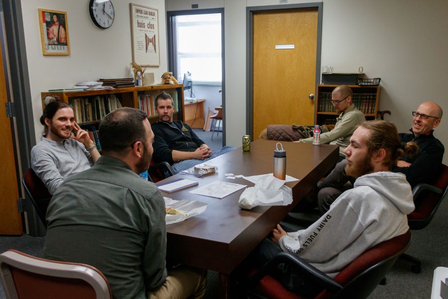 6 people sit at a conference table talking and laughing