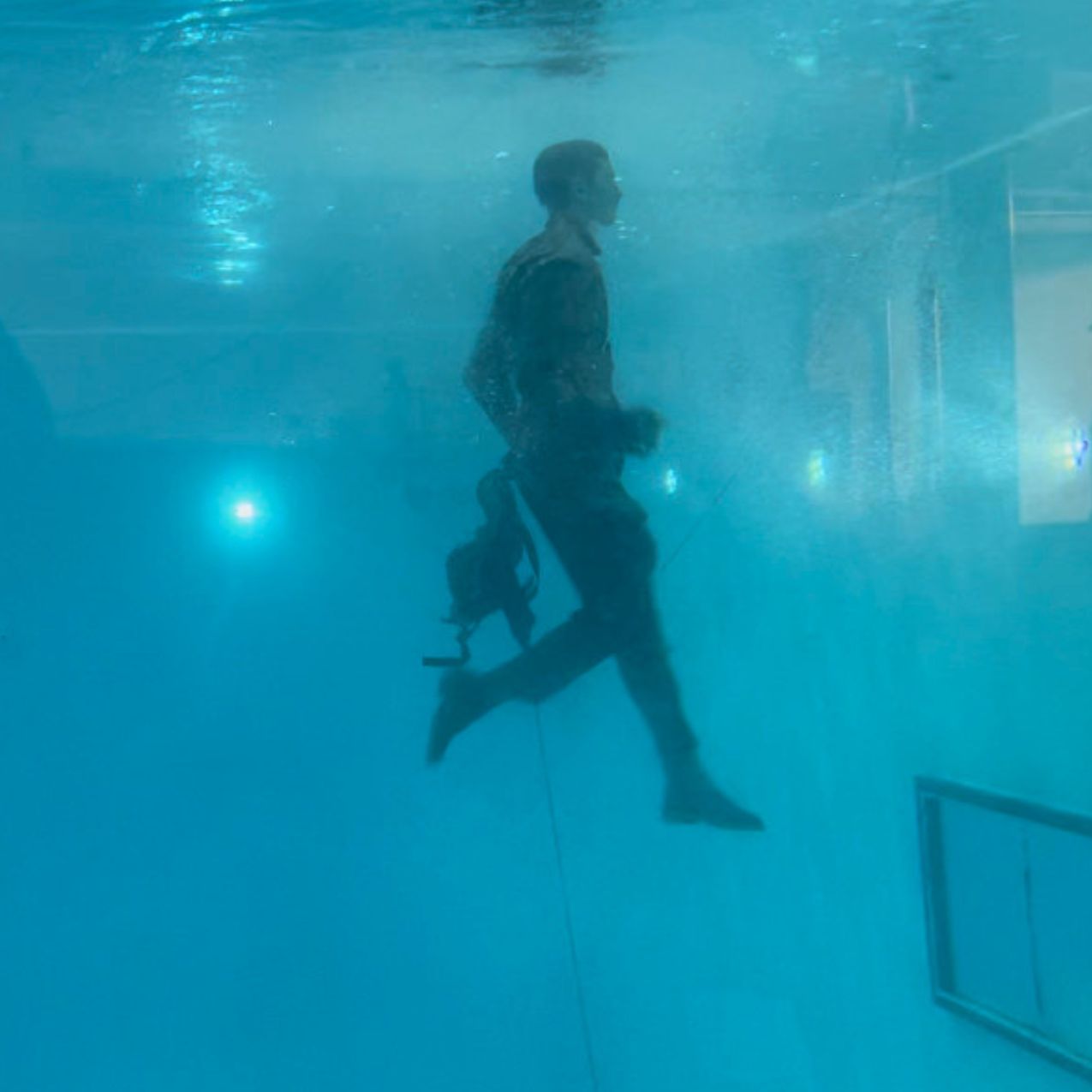 An ISU ROTC cadet does water training by jumping into the pool fully clothed with equipment. This photo is taken underwater and shows the student submerged in the water.
