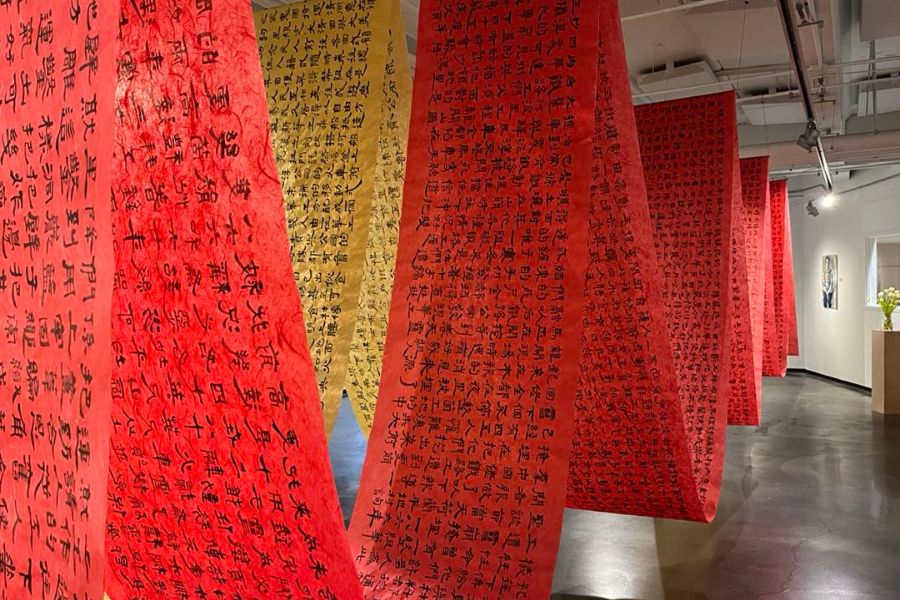 A red and a yellow banner, both covered in Chinese caligraphy, hang in swoops from the Davis Gallery ceiling
