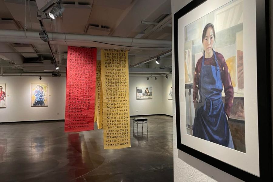 Self portrait of Yidan Guo in the Davis Gallery. In the background red and yellow banners hang from the ceiling