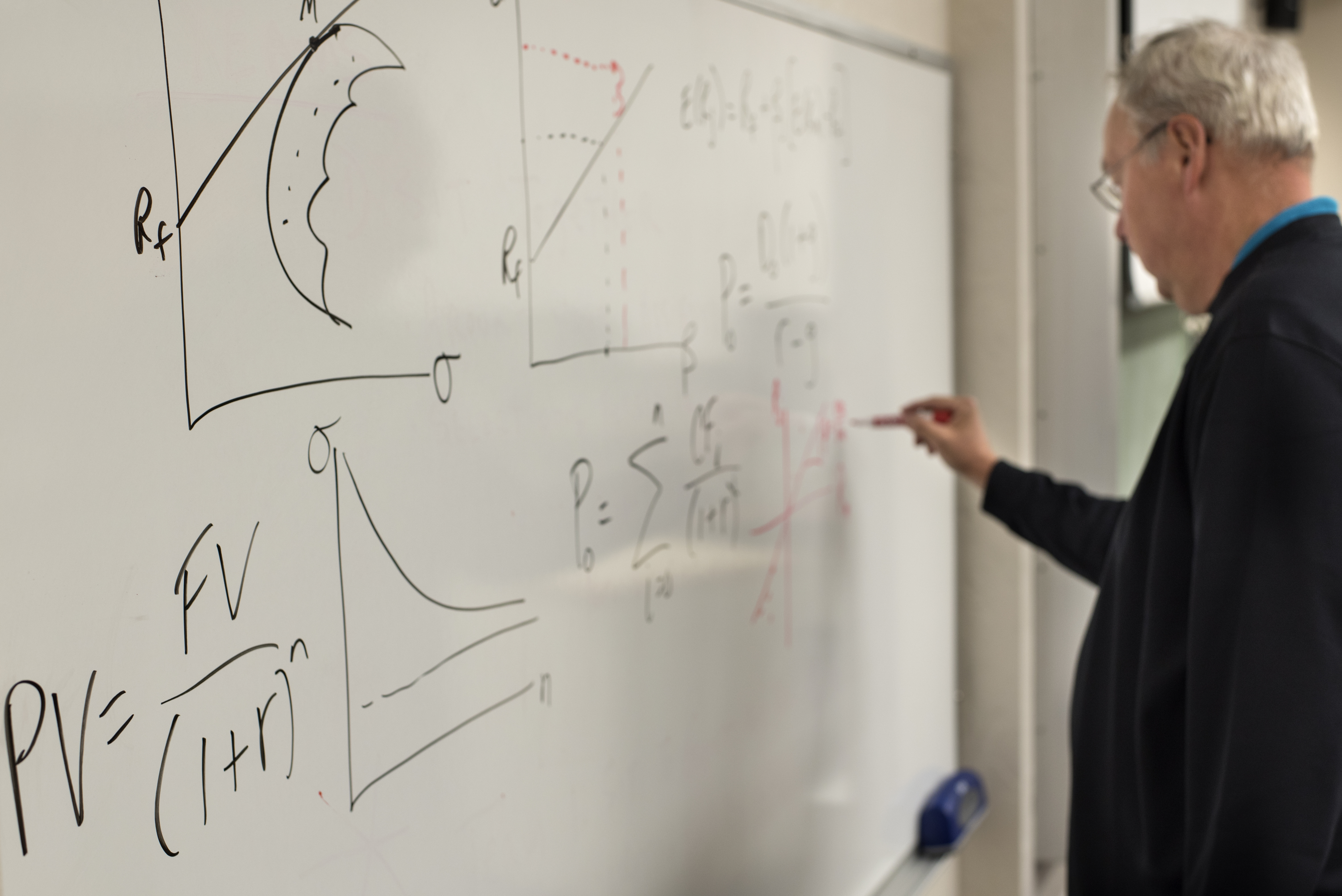 Professor Byers writing on a whiteboard during a finance lecture