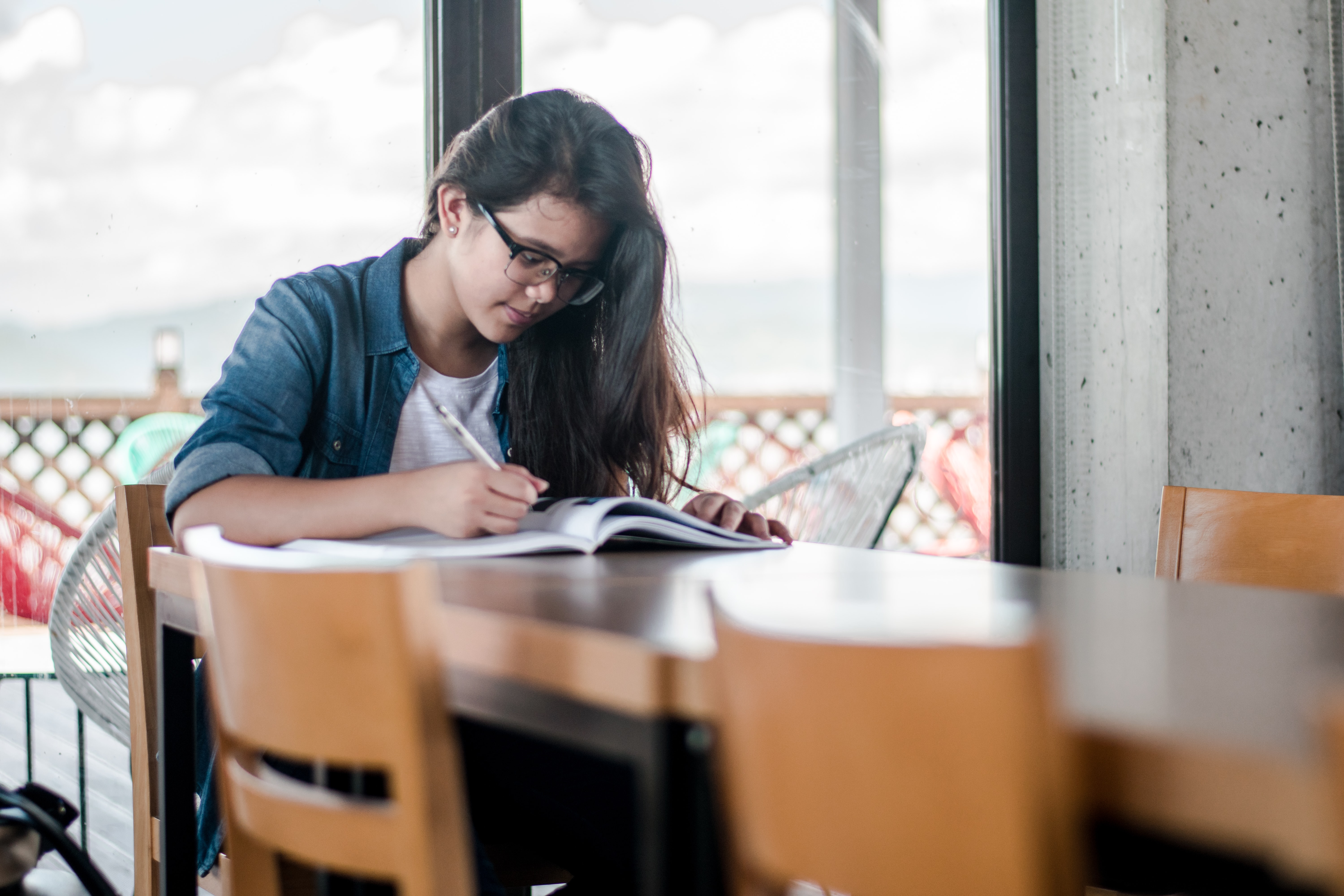 Student sitting at a table writing in a notebook