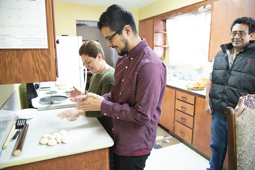 Man preparing food in a kitchen with family