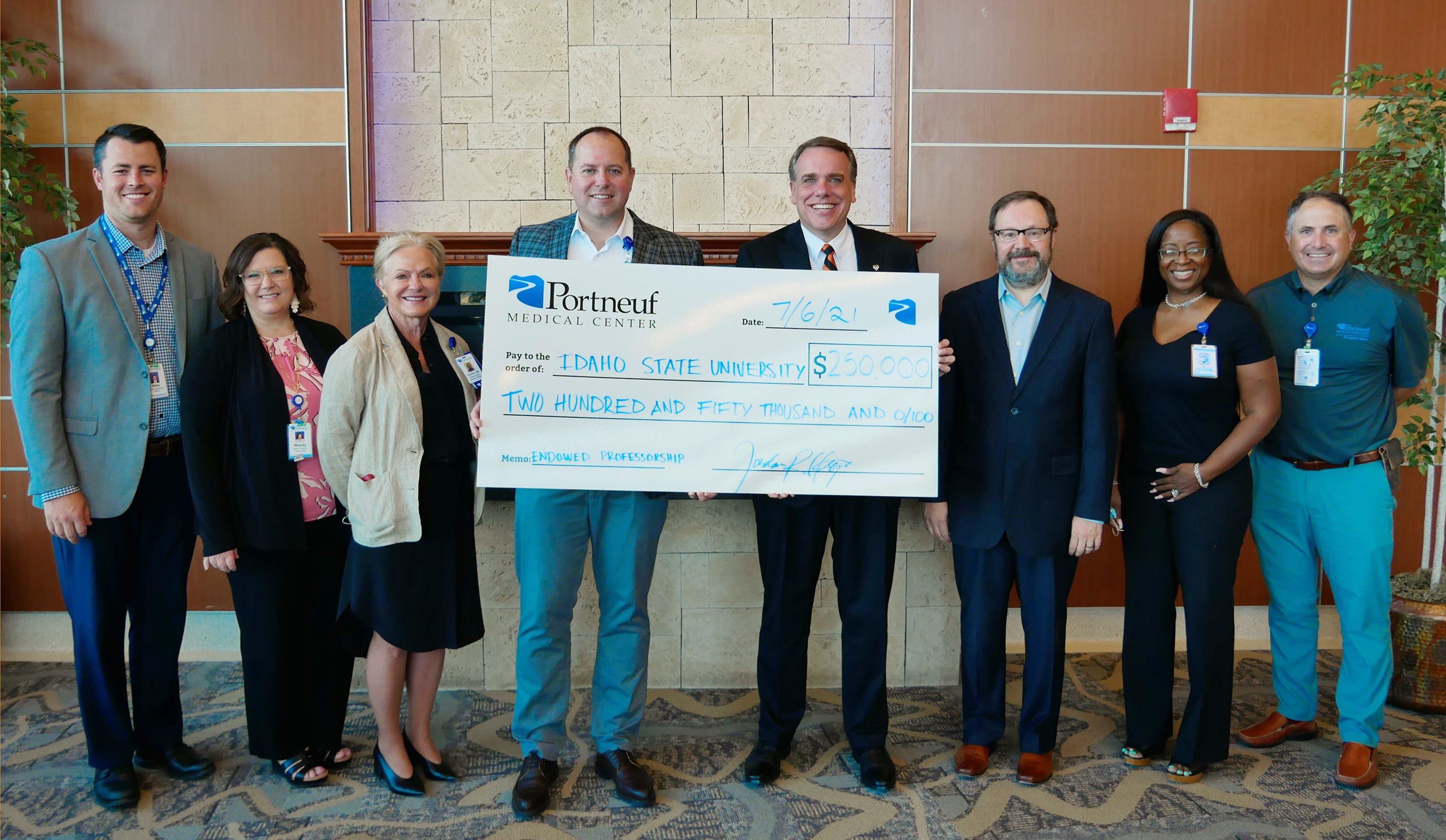 Group of people holding a large check to celebrate a new professorship