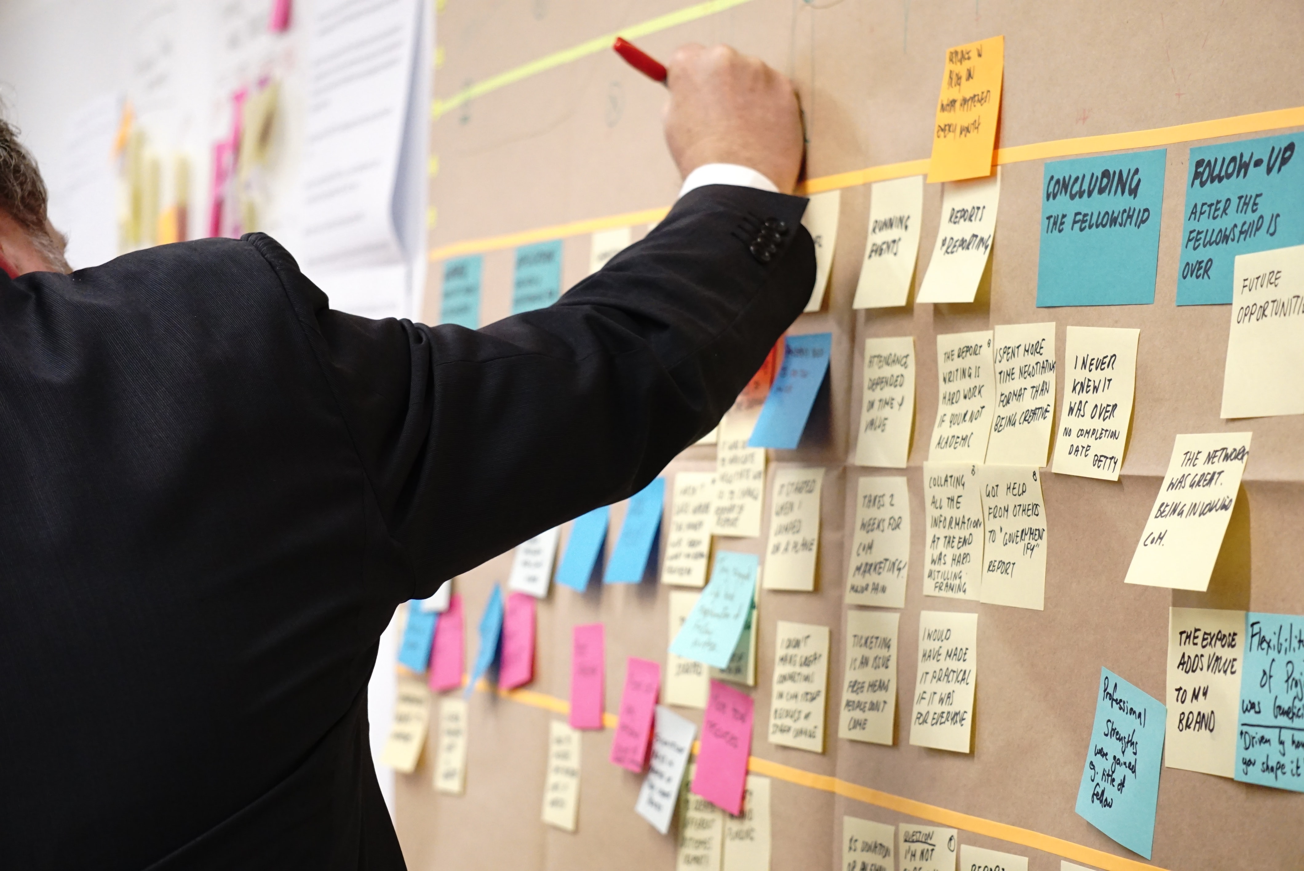 Person writing on a sticky note posted to a wall