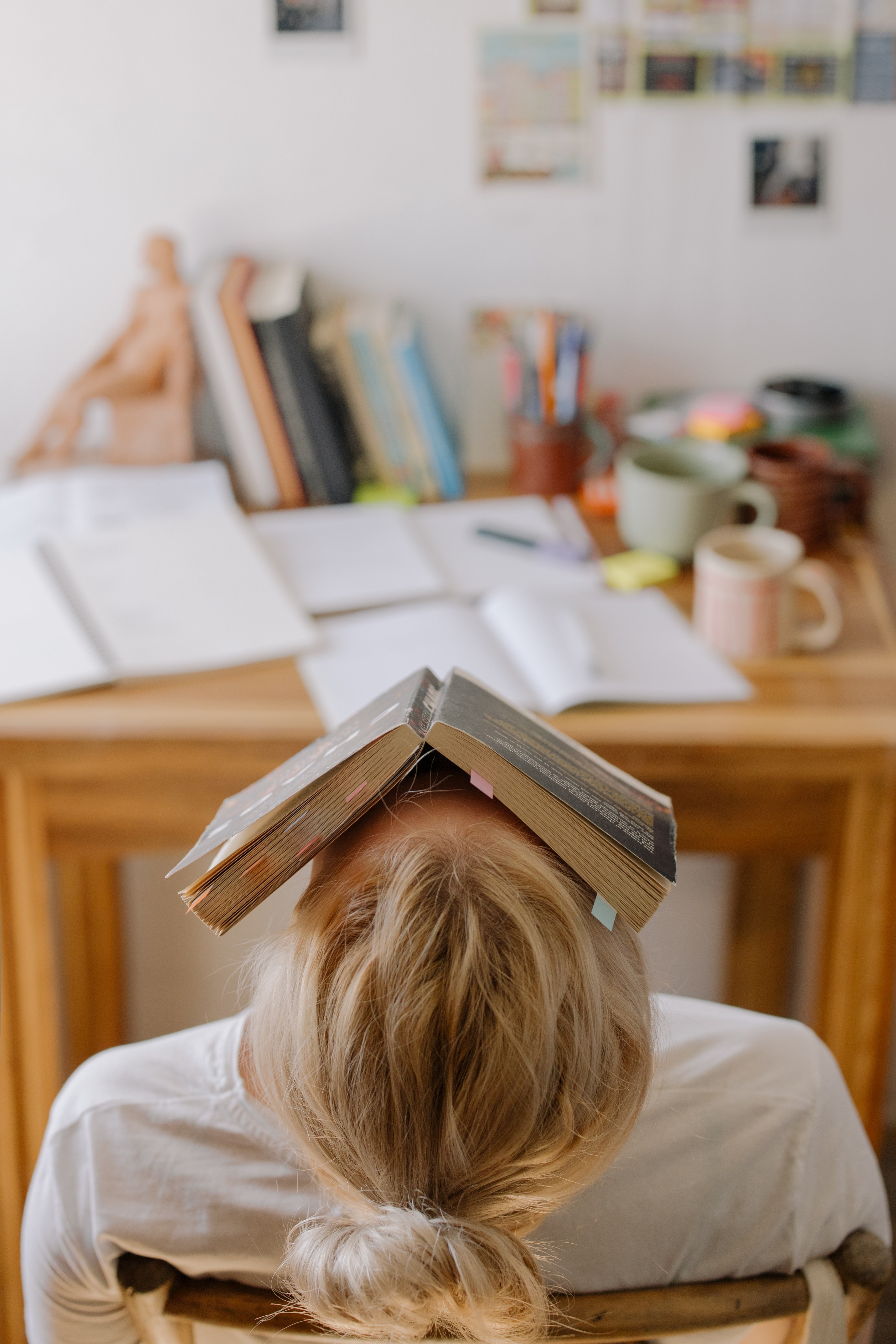 A student sitting in a chair with a book over her face