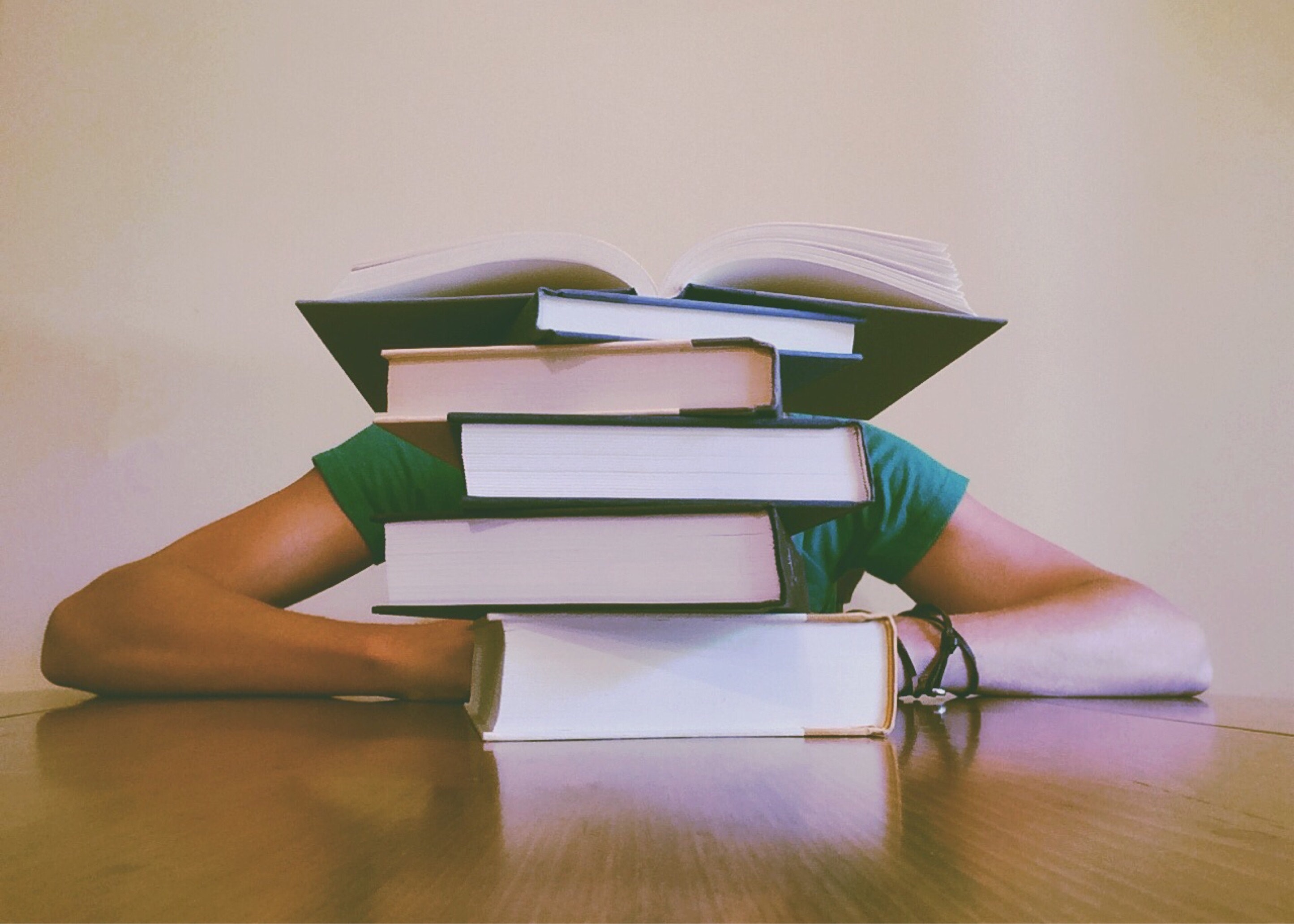 A stressed student overwhelmed with a stack of textbooks