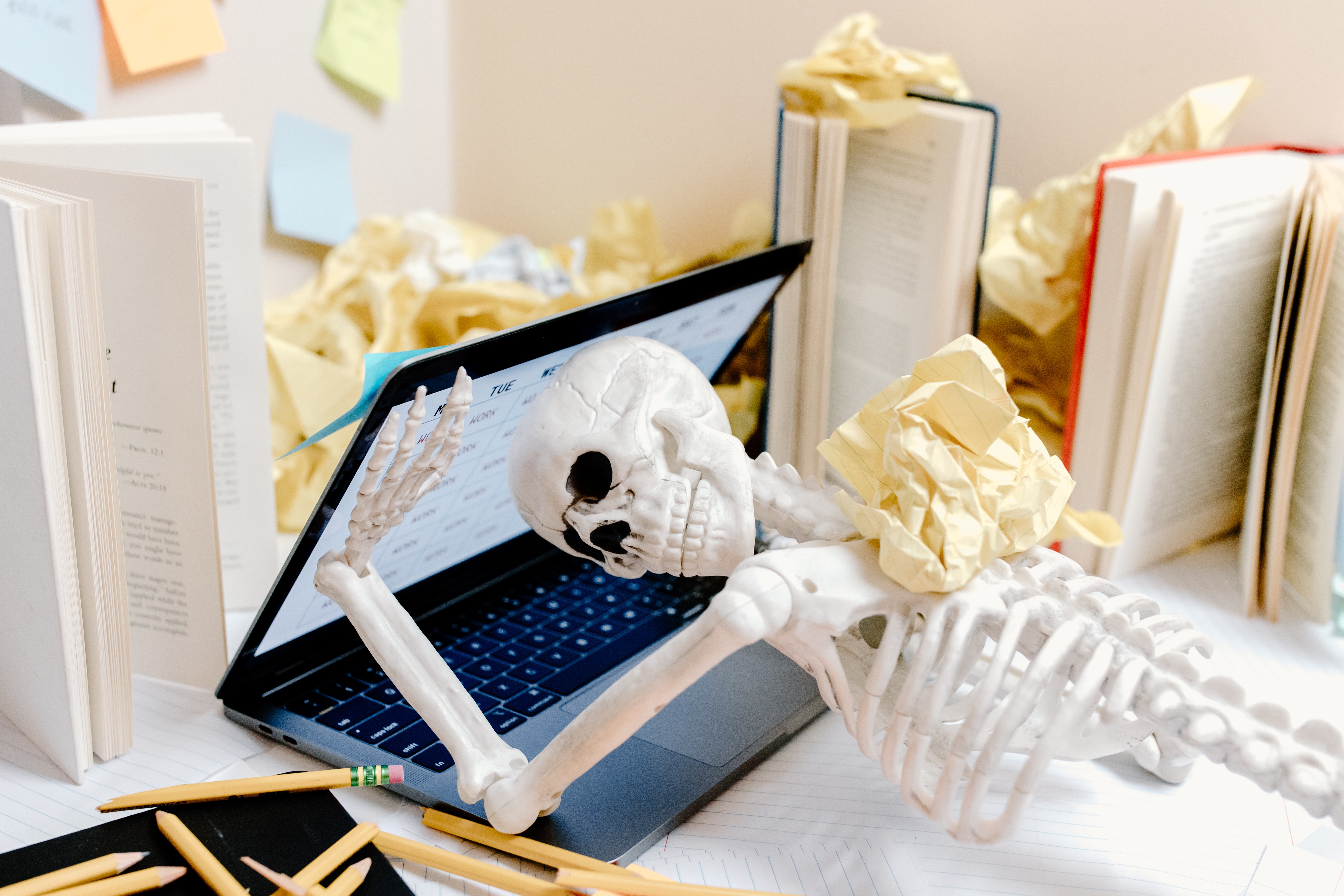 A skeleton with a laptop trying to close on its head