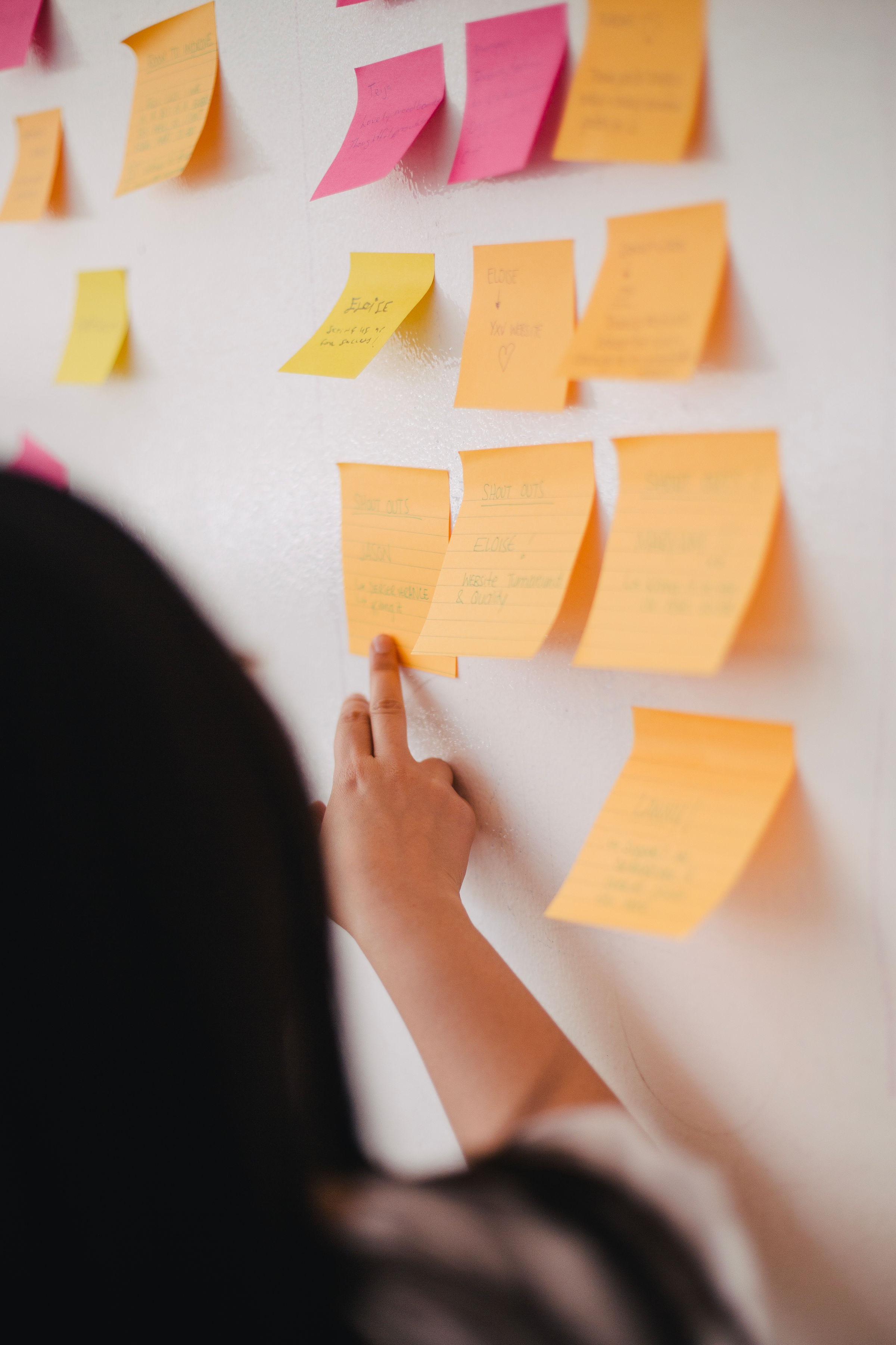 Person grabbing at a wall of sticky notes