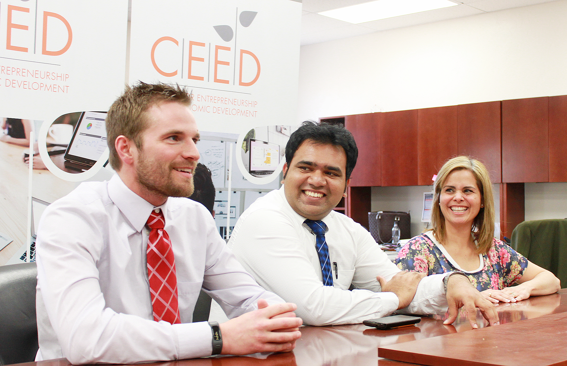 Students smiling at a CEED desk