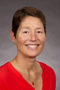 A smiling woman with medium skin tone and short dark hair wearing a red shirt and smiling.