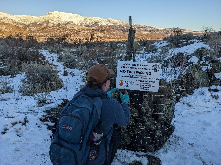 Person hanging a no trespassing sign for research