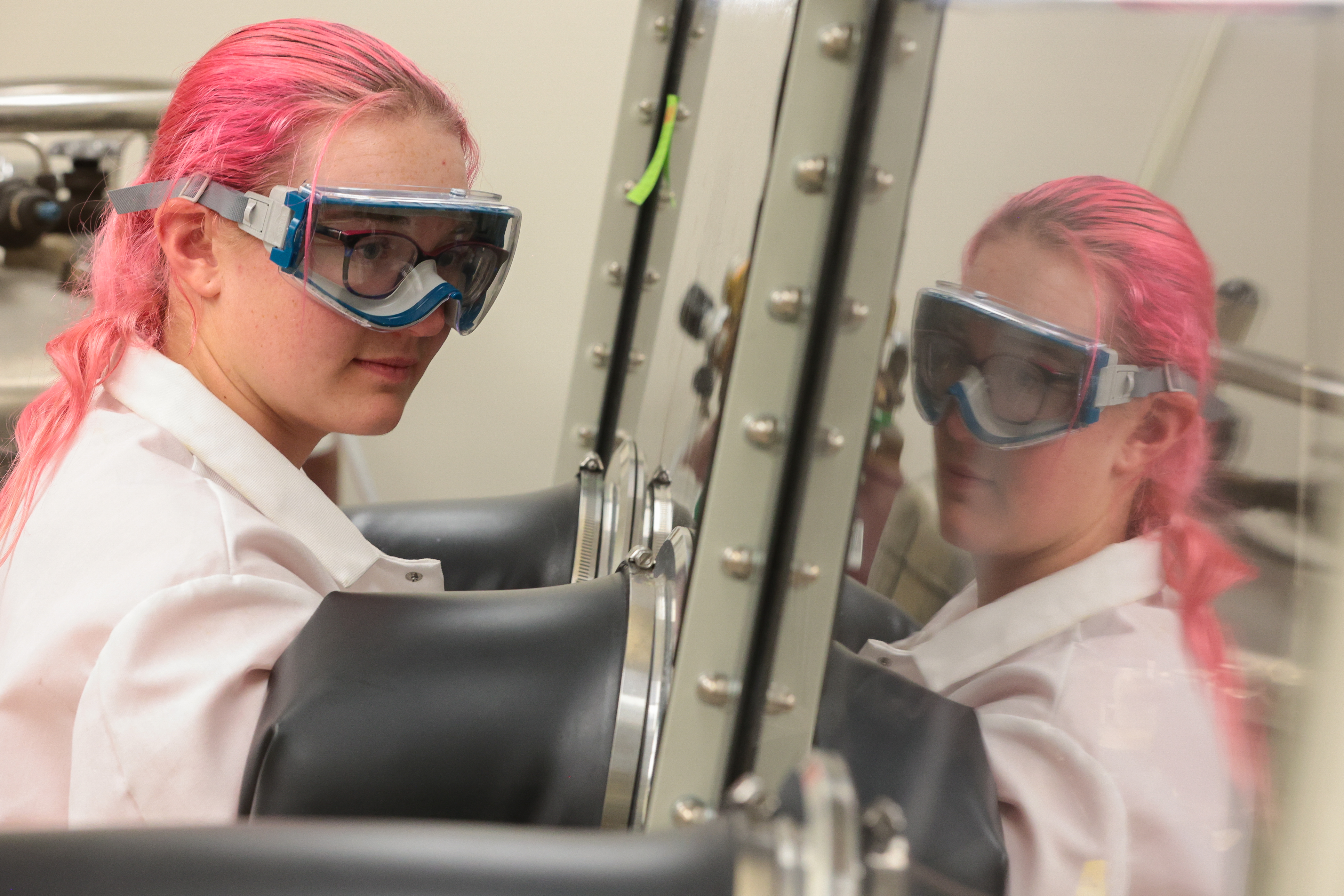 Photo of a student in a labratory setting working with an enclosed glove box.