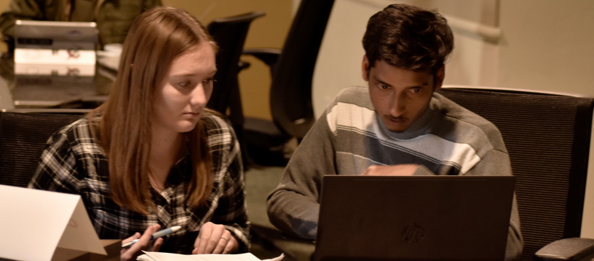 Male and Female student working together and looking at a laptop.