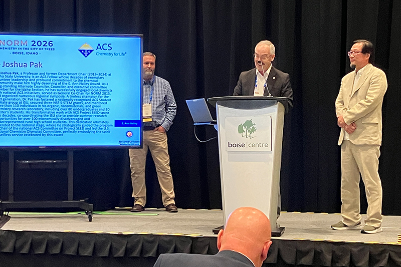 osh Pak, professor of chemistry, stands on stage while receiving his E. Ann Nalley Regional Award for Volunteer Service to the American Chemical Society in Boise, Idaho.