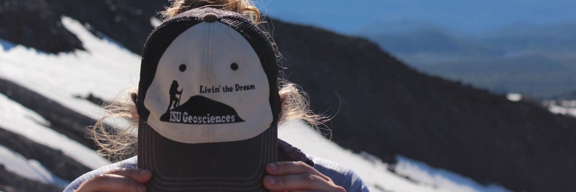 Student showing the logo on her ISU Geosciences hat