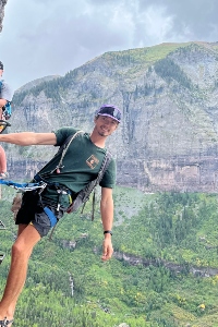 Jack Mason hanging from a cliffside