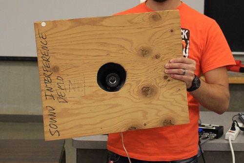 A speaker behind a piece of wood