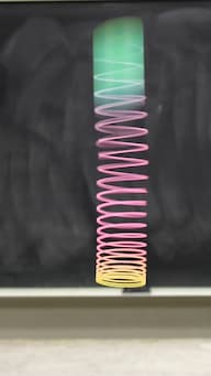A slinky being held from a hand hanging at rest.