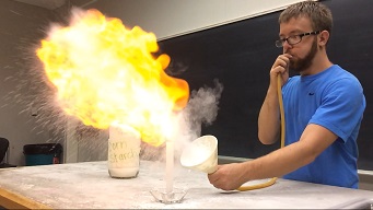 Someone blowing cornstarch into a flame causing a fireball