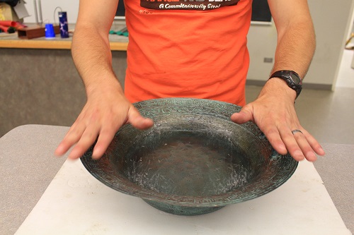 An old chinese bowl with someone putting their hands on it