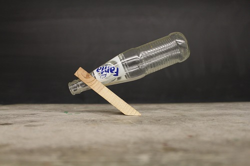 A bottle balancing inside of a wooden block