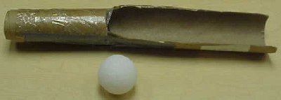 A ball sitting next to a cardboard tube with a chunk cut out